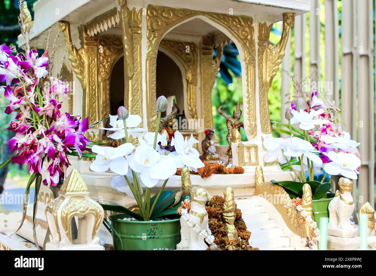 Un santuario nel giardino, adornato di fiori e statue, favorisce un ambiente tranquillo e spirituale Foto Stock