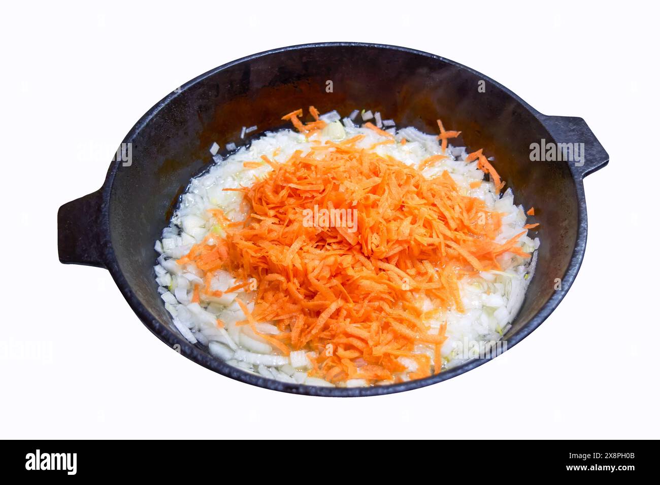 Padella in ghisa su cui vengono fritte cipolle e carote, isolare su sfondo bianco, primo piano. Foto Stock