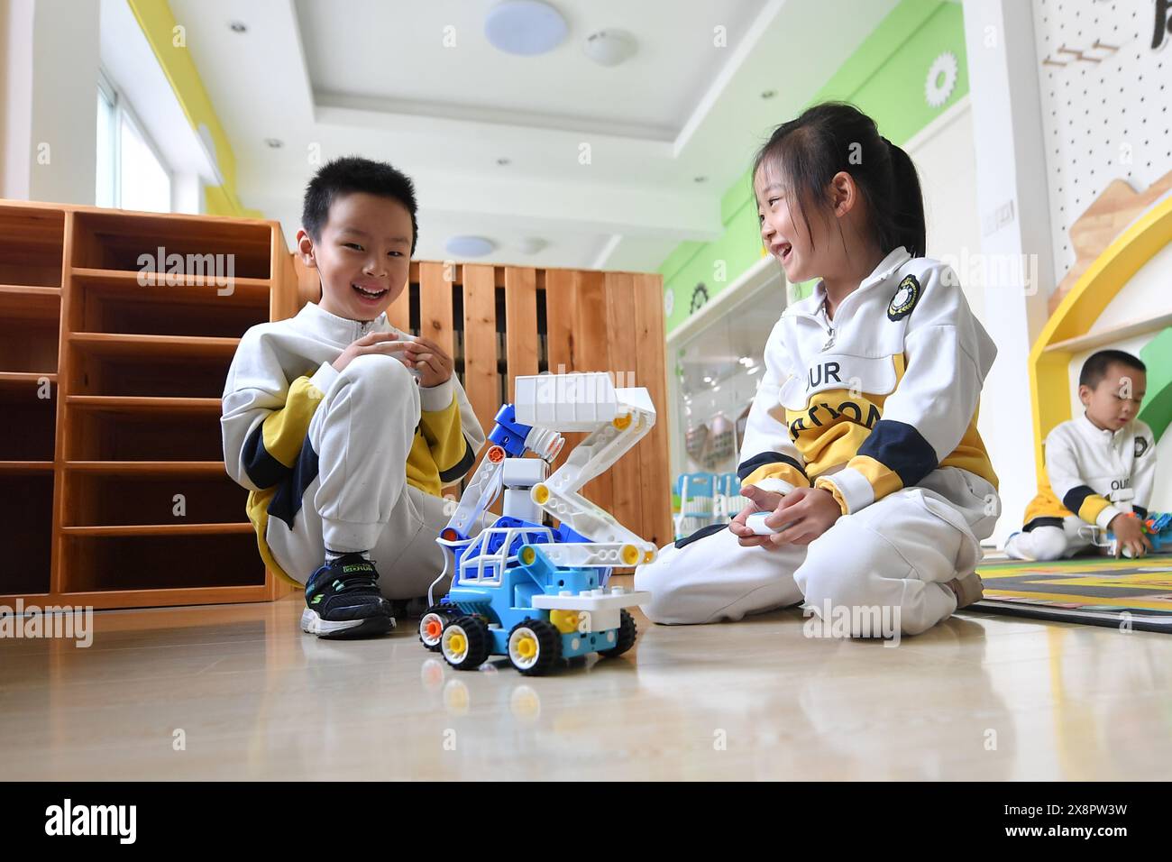 QINGDAO, CINA - 27 MAGGIO 2024 - i bambini gestiscono un'auto da gioco intelligente durante una popolare attività educativa della settimana della Scienza in un asilo di Qingdao Foto Stock