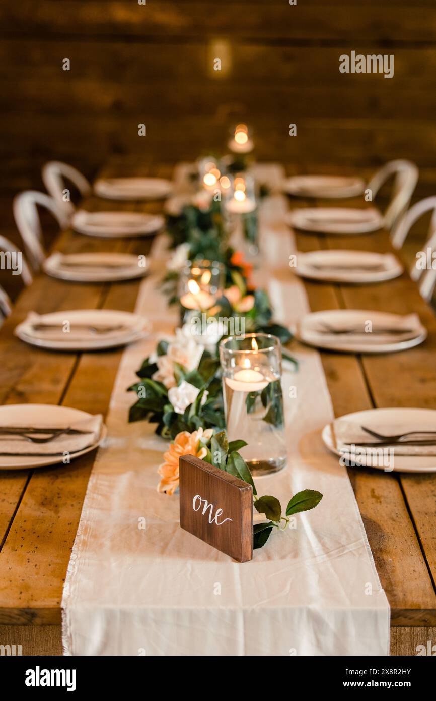 Rustico tavolo per ricevimenti nuziali con candele e vegetazione Foto Stock