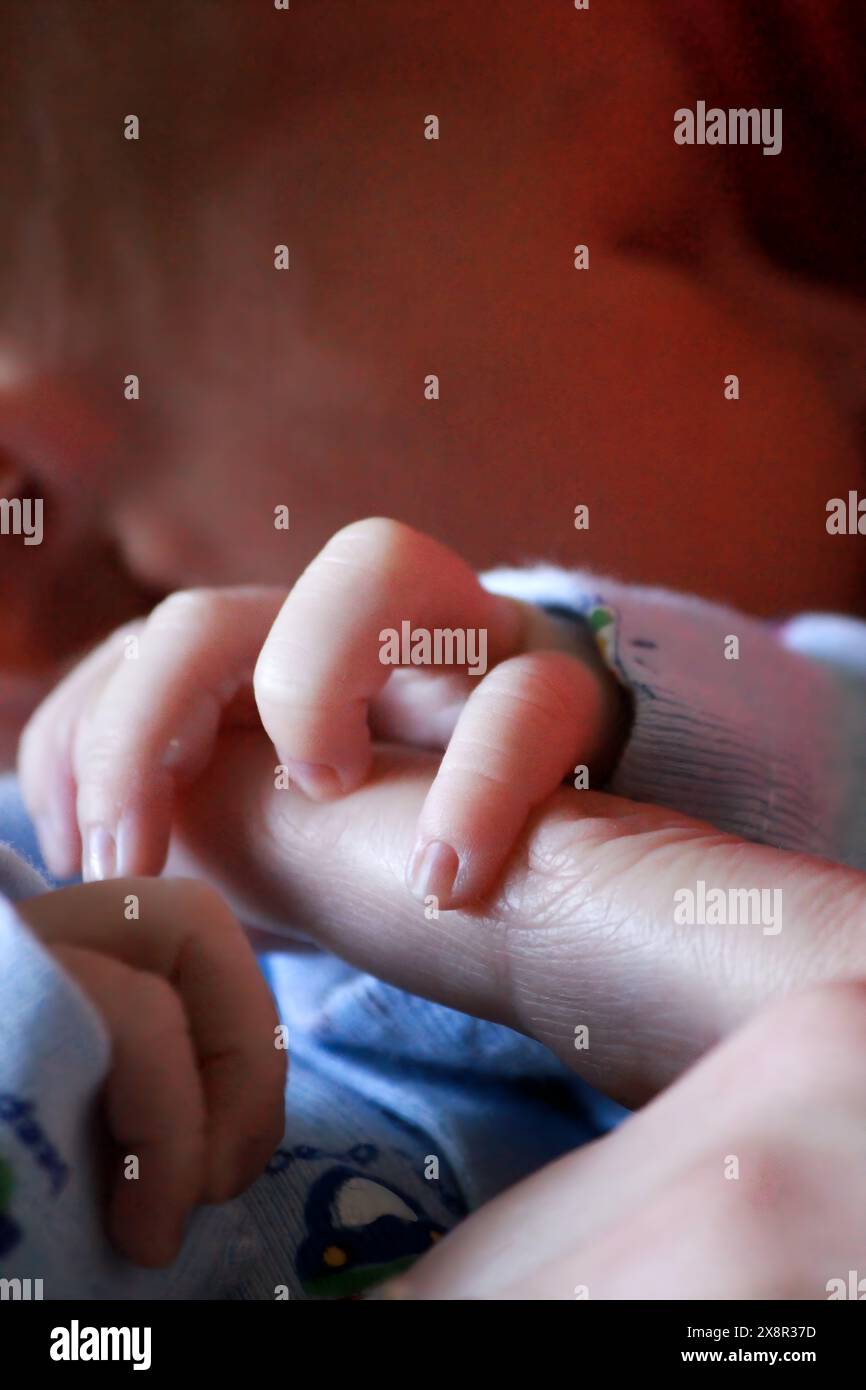 La minuscola mano del neonato afferra delicatamente il dito della madre Foto Stock
