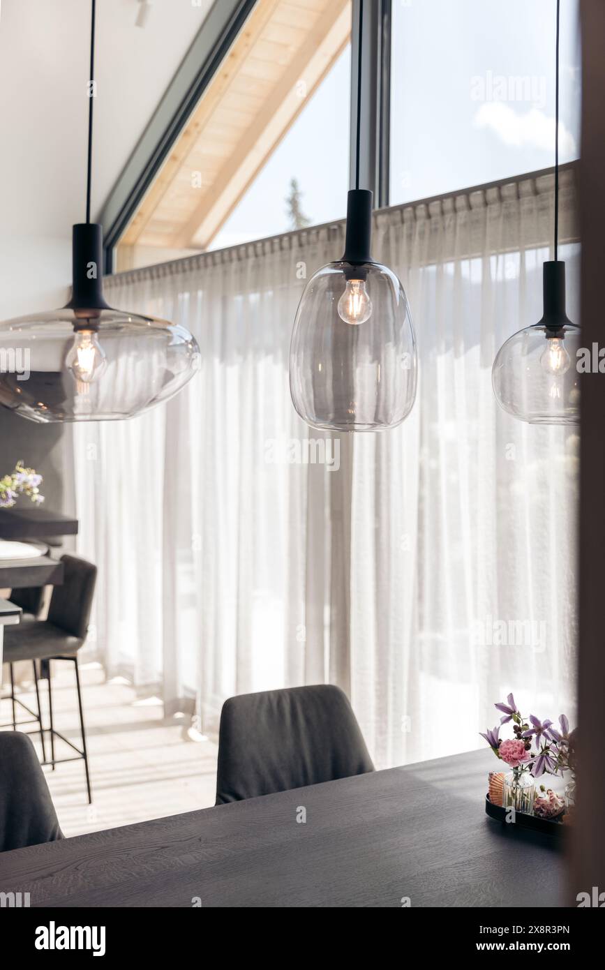 Moderna zona pranzo con luci a sospensione in vetro e decorazioni floreali Foto Stock