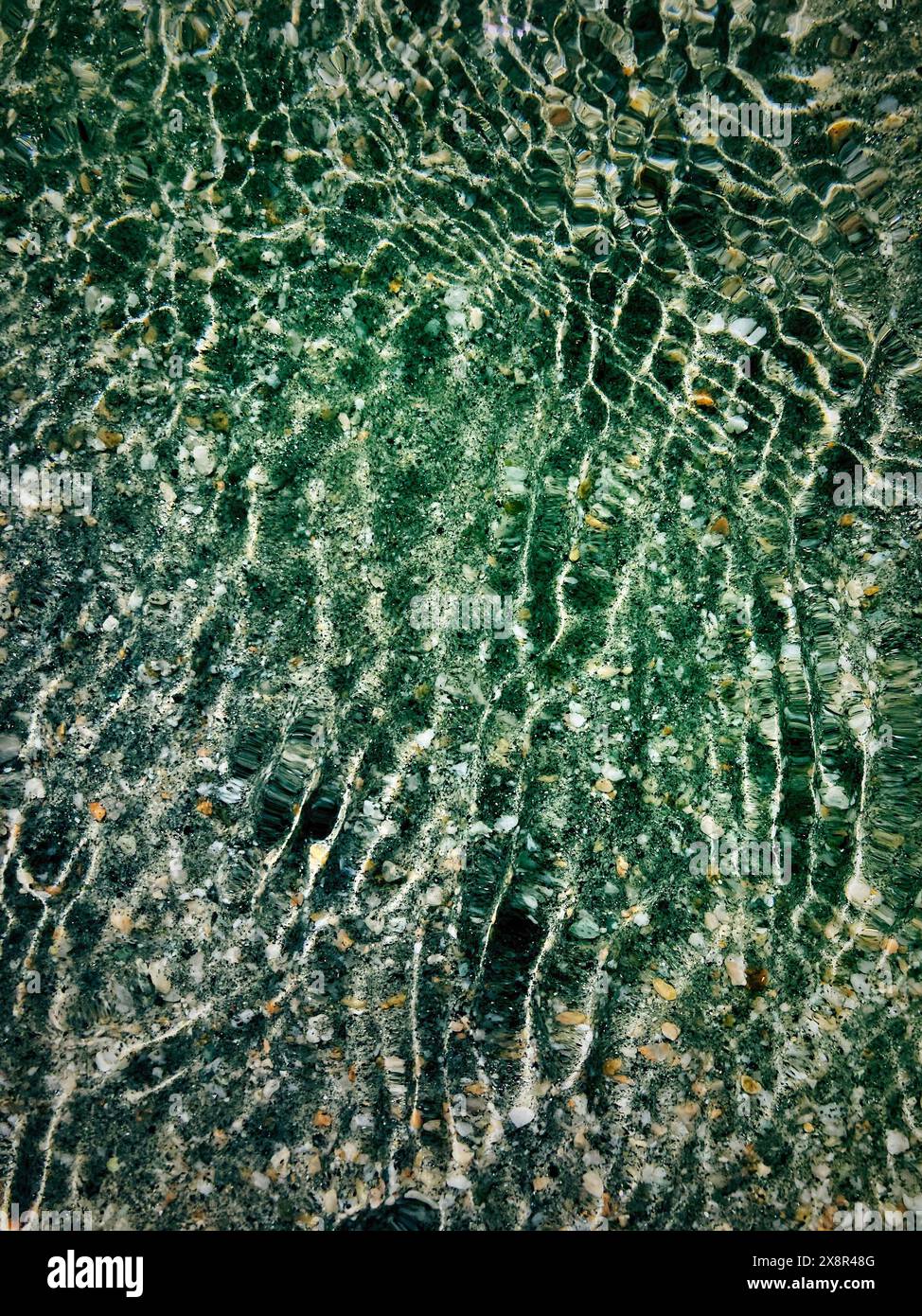 Ondulazione dell'acqua con ciottoli e sabbia Foto Stock