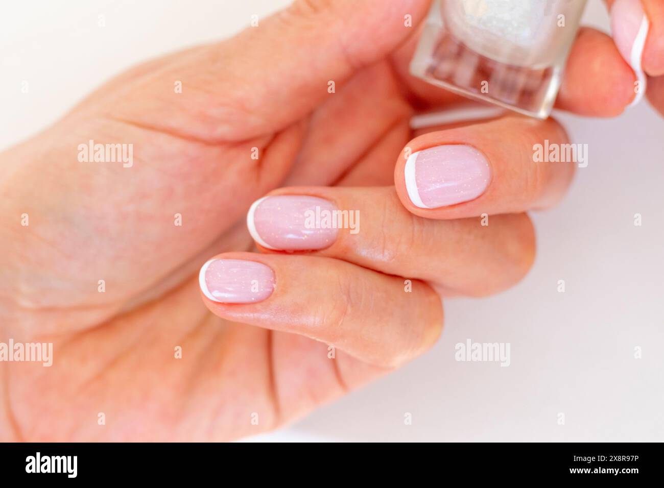 Foto della mano della bella donna che tiene una bottiglia di smalto per unghie Foto Stock