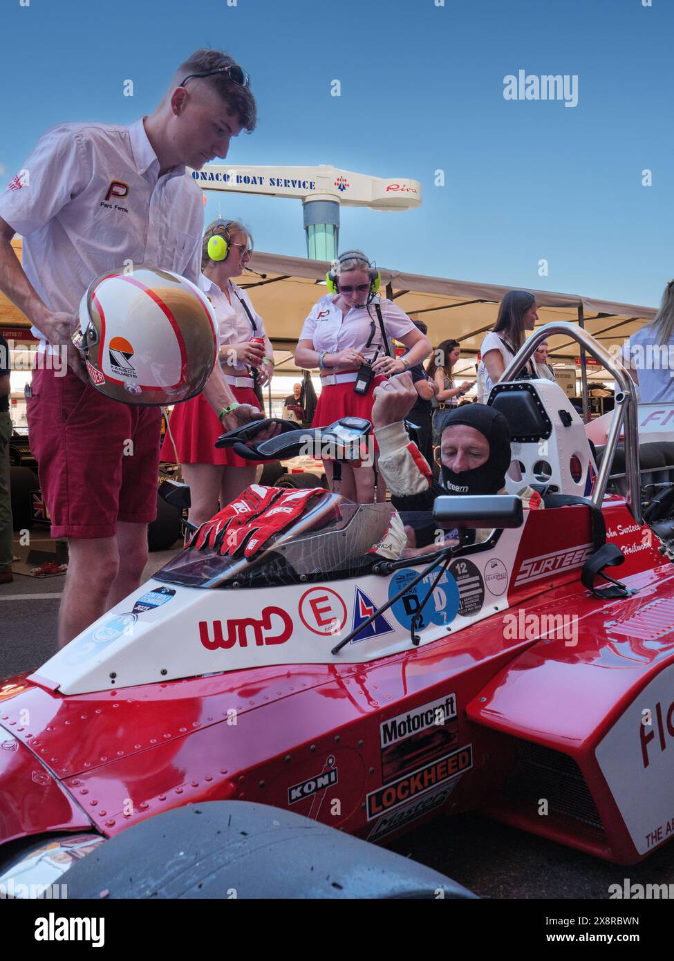 Un uomo e due donne in rosso che preparano una Surtees TS9B rossa classica auto da corsa al Gran Premio storico di Monaco, Monte Carlo, Monaco, Sud della Francia Foto Stock