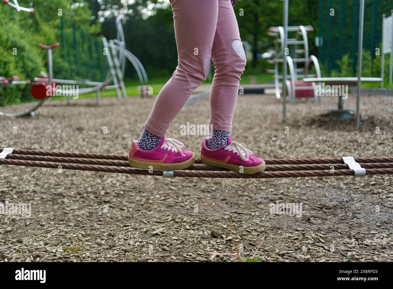 Le gambe dei bambini piccoli vanno su una corda in un campo sportivo per bambini in estate Foto Stock