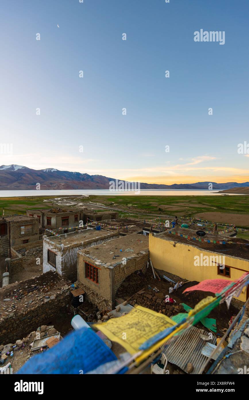 Terreni agricoli e borghi con bandiere di preghiera appese sui tetti, accanto al TSO Moriri (lago Moriri) ad alta quota nell'altopiano di Changthang, Ladakh, India. Foto Stock