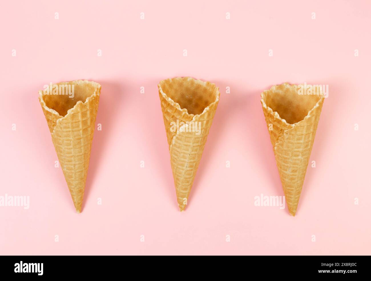 Vista dall'alto di tre coni di gelato per waffle su sfondo rosa. Carta da parati estiva, piano, spazio per copie. Foto Stock