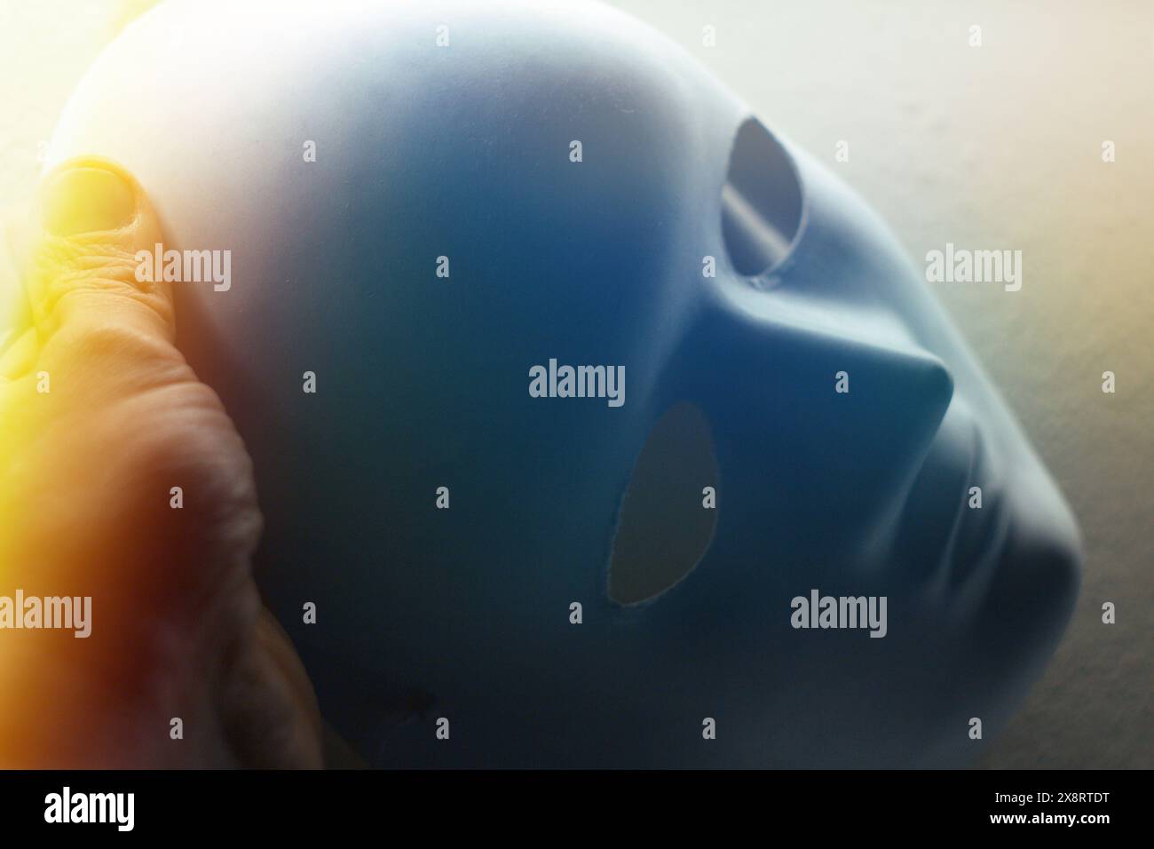 Primo piano di una mano che prende una maschera, cattivo uomo bugiardo indossare buona maschera falso concetto di viso. Foto Stock