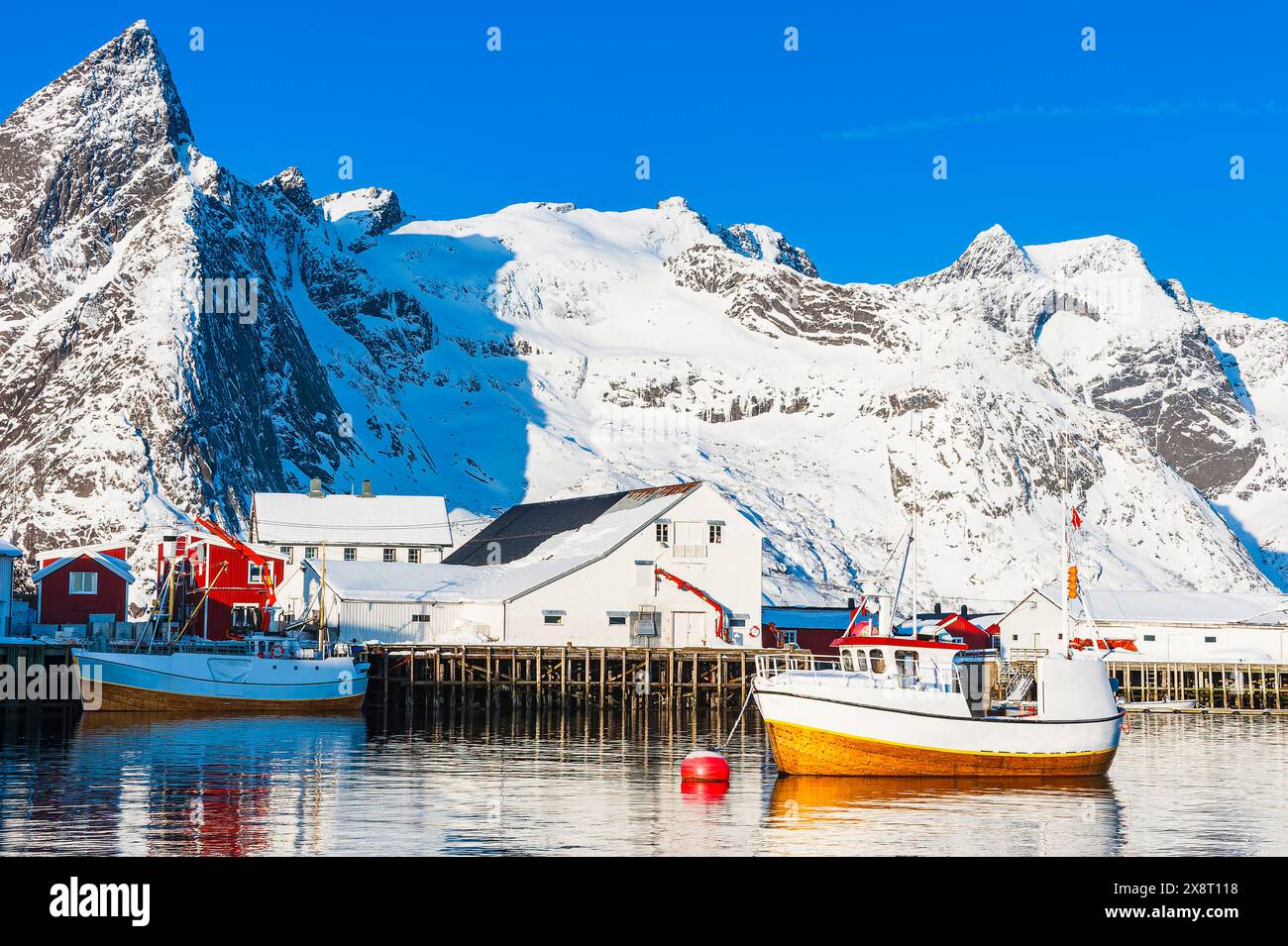 La barca è vista nel porto, con una maestosa montagna invernale che torreggia sullo sfondo. La scena cattura il contrasto tra il vaso artificiale AN Foto Stock