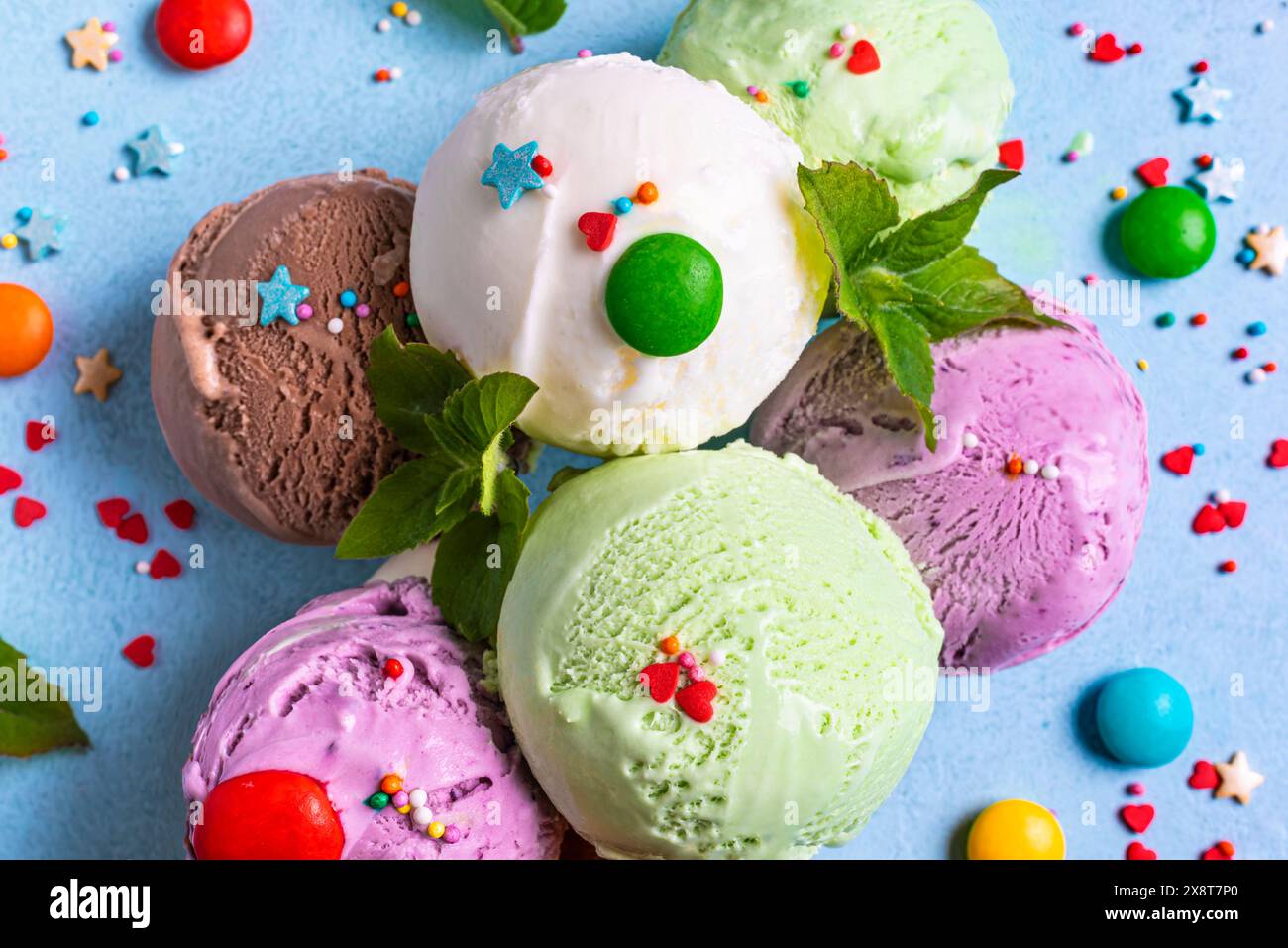 Vari cucchiai per gelato con spolverini di zucchero e foglie di menta da vicino. Yogurt biologico congelato nel deserto estivo. Foto Stock