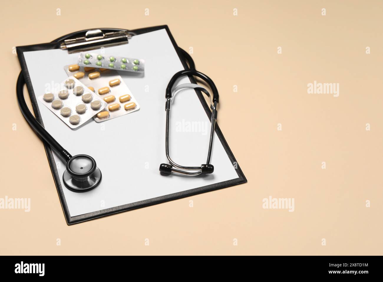 Stetoscopio, pillole e appunti su sfondo beige. Spazio per il testo Foto Stock