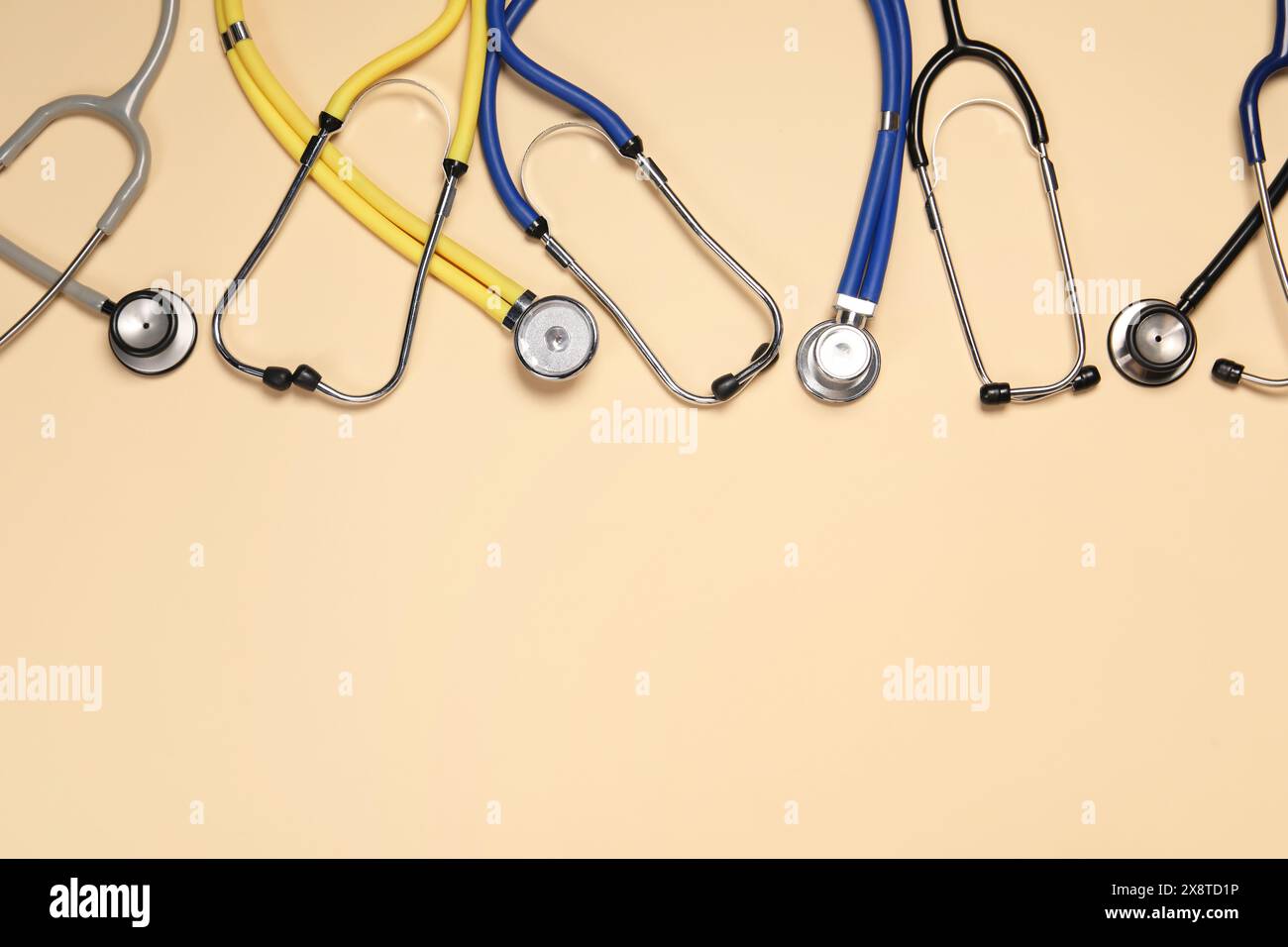 Stetoscopi su sfondo beige, piatto. Spazio per il testo Foto Stock