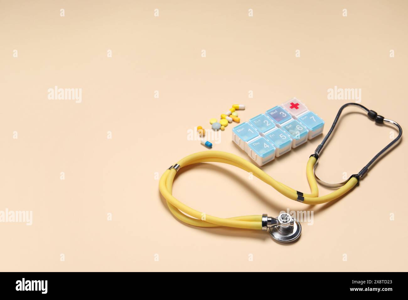 Stetoscopio e pillole su sfondo beige. Spazio per il testo Foto Stock