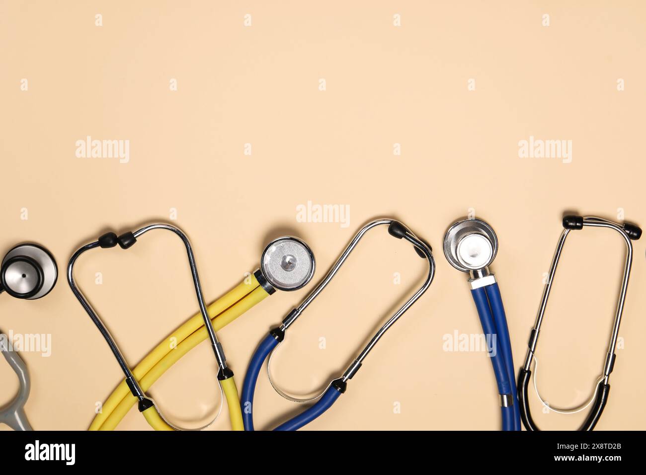 Stetoscopi su sfondo beige, piatto. Spazio per il testo Foto Stock