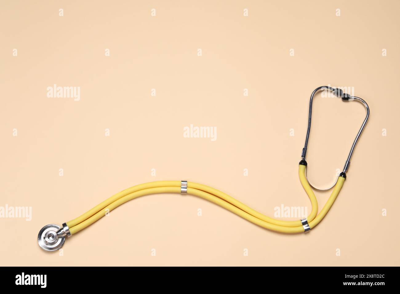 Stetoscopio su sfondo beige, vista dall'alto. Spazio per il testo Foto Stock