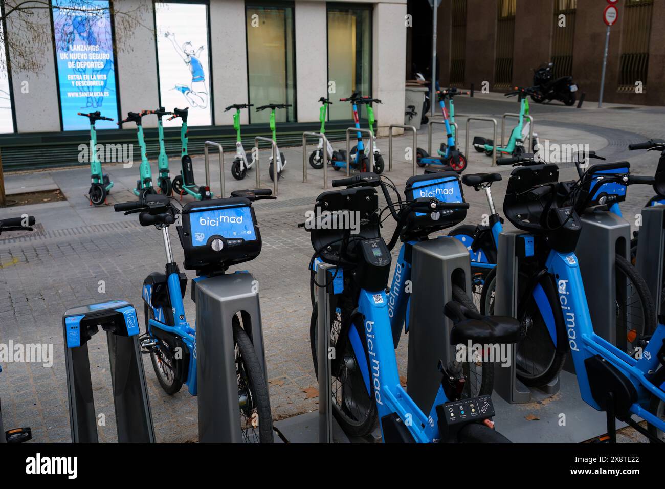 Madrid, Spagna. 13 febbraio 2024 - noleggio di biciclette da città e scooter elettrici parcheggiati sul marciapiede. Foto Stock