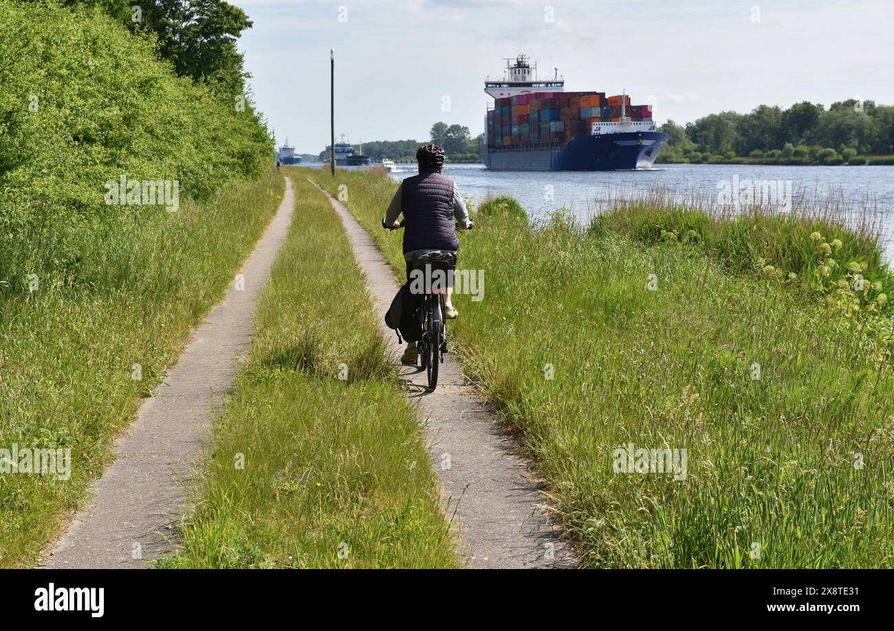 In bicicletta con una nave portacontainer sul canale di Kiel, Kiel, Schleswig-Holstein, Germania Foto Stock