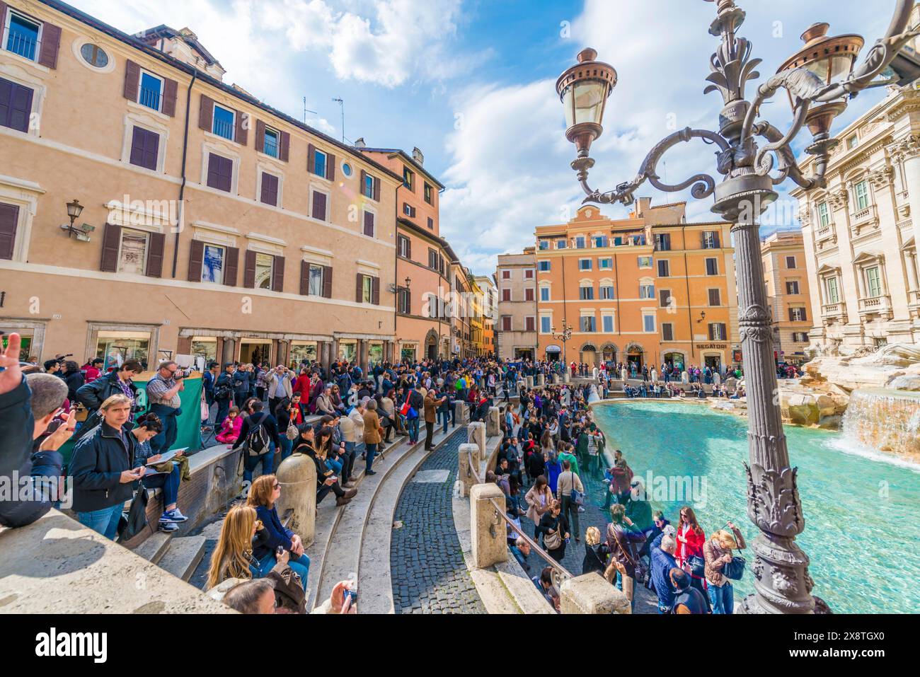 Fontana di Trevi, lampada di strada e vecchi edifici con la folla di persone in un giorno di sole a Roma, Lazio, Italia Foto Stock