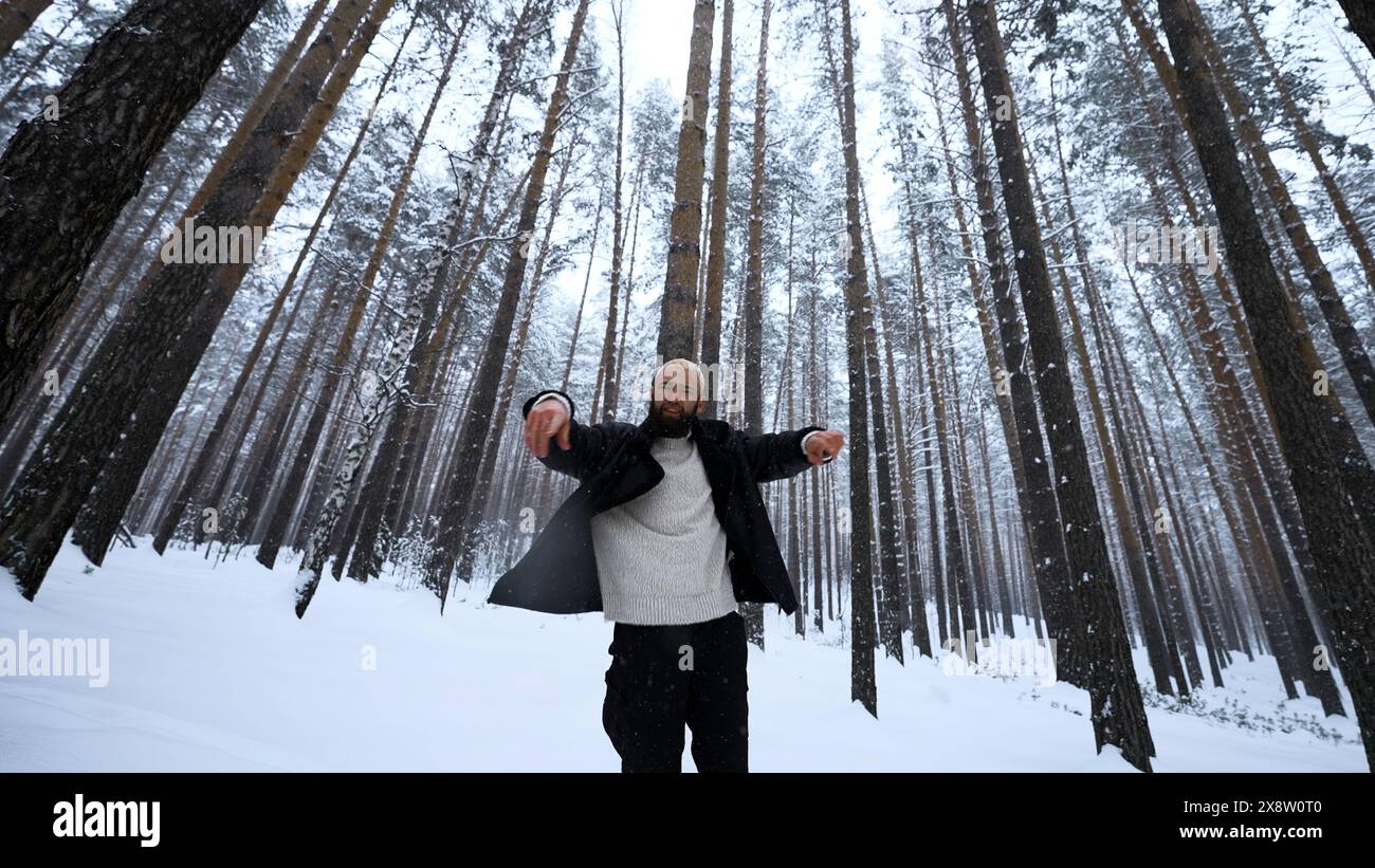 Ritratto di un bel giovane barbuto in abiti caldi in piedi all'aperto nel parco il giorno invernale. Supporto. Modello biondo hipster nei legni. Foto Stock