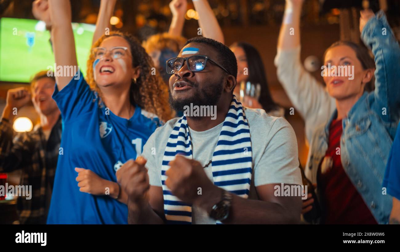 I membri del Club di calcio tifanno per la propria squadra, giocando in una finale di Coppa Internazionale. Tifosi di supporto in piedi in un bar, esultare, alzare le mani e urlare. Gli amici celebrano la vittoria dopo il gol. Foto Stock