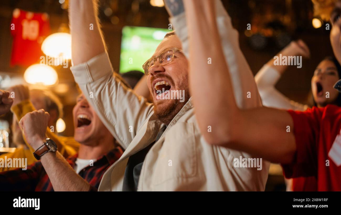 Gruppo di amici che guardano una partita di calcio dal vivo in TV in un bar dello sport. Tifosi contenti che bramano e urlano. I giovani festeggiano quando la squadra segna un gol e vince la Coppa del mondo di calcio. Movimento lento. Foto Stock