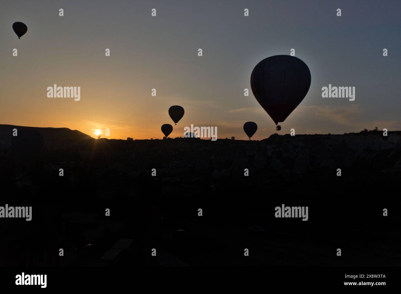Le mongolfiere si stagliano contro il cielo dell'alba in Cappadocia, creando una scena serena e accattivante. I palloncini fluttuano agevolmente sopra la rugge Foto Stock