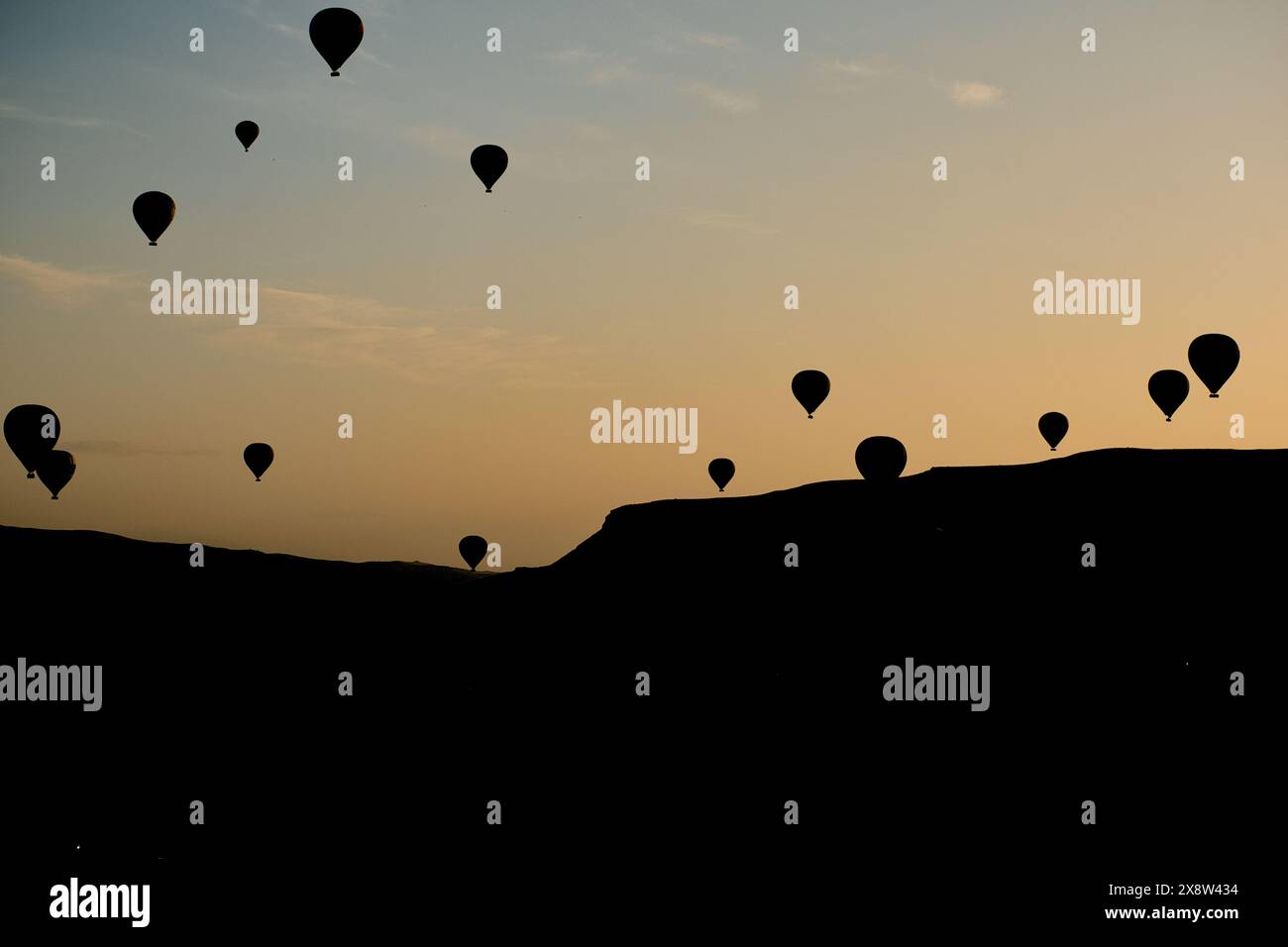 Le mongolfiere si stagliano contro il cielo dell'alba in Cappadocia, creando una scena serena e accattivante. I palloncini fluttuano agevolmente sopra la rugge Foto Stock