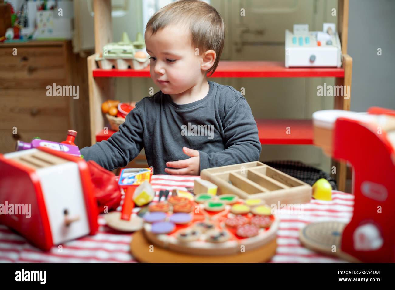 Il bambino gioca come cuoco con giocattoli di legno. Gioco simbolico, apprendimento, crescita. Foto Stock