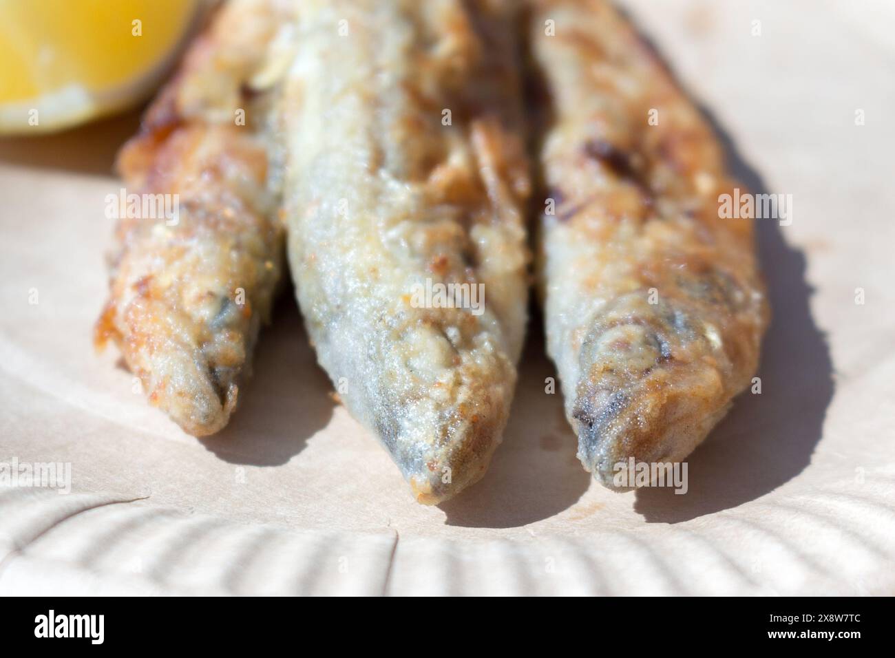Delizioso odore fritto su un piatto di cartone con una fetta di limone, vista dall'alto. Specialità di pesce, fast food. Foto Stock