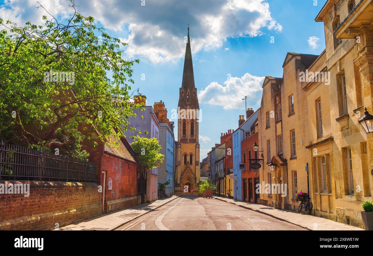 Oxford, Inghilterra, Regno Unito - 19 maggio 2024: Vista su strada dei negozi locali e della vecchia chiesa anglicana e delle case di Oxford City, di giorno Foto Stock