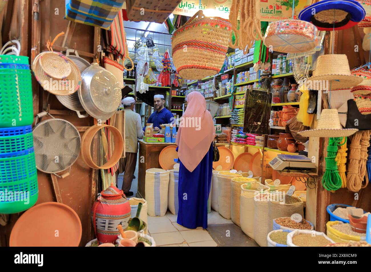 Un negozio di articoli per la casa e alimentari con una cliente donna con Hijab all'interno nel mercato di Ghardaia. Valle di Mzab. Provincia di Ghardaia. Sahara settentrionale. Algeria Foto Stock