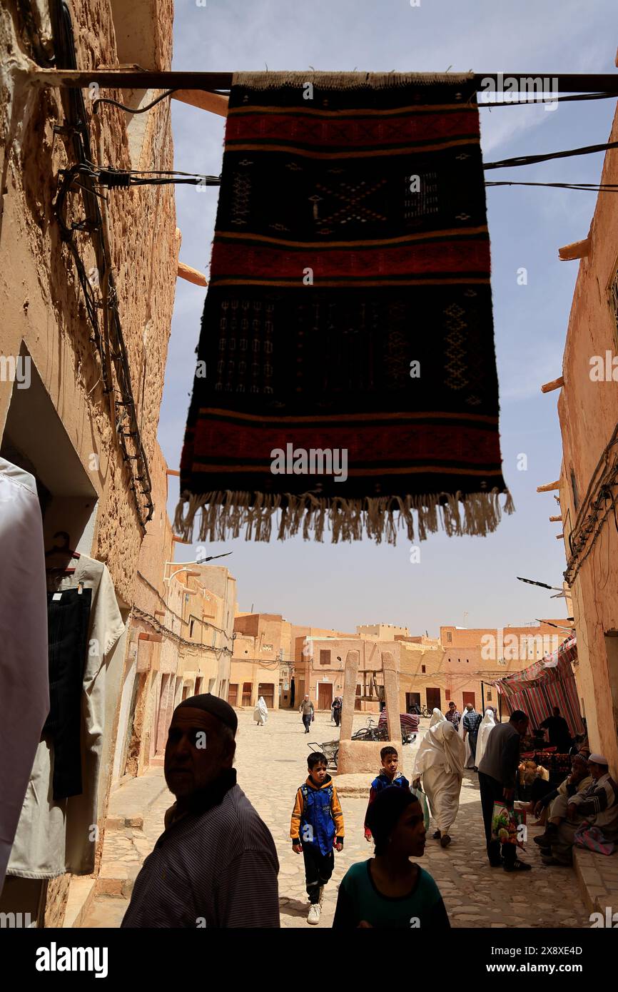 Piazza del mercato circondata da architetture tradizionali con un tappeto appeso in primo piano. Ksar beni Isguen. Provincia di Ghardaia. Sahara settentrionale. Algeria Foto Stock