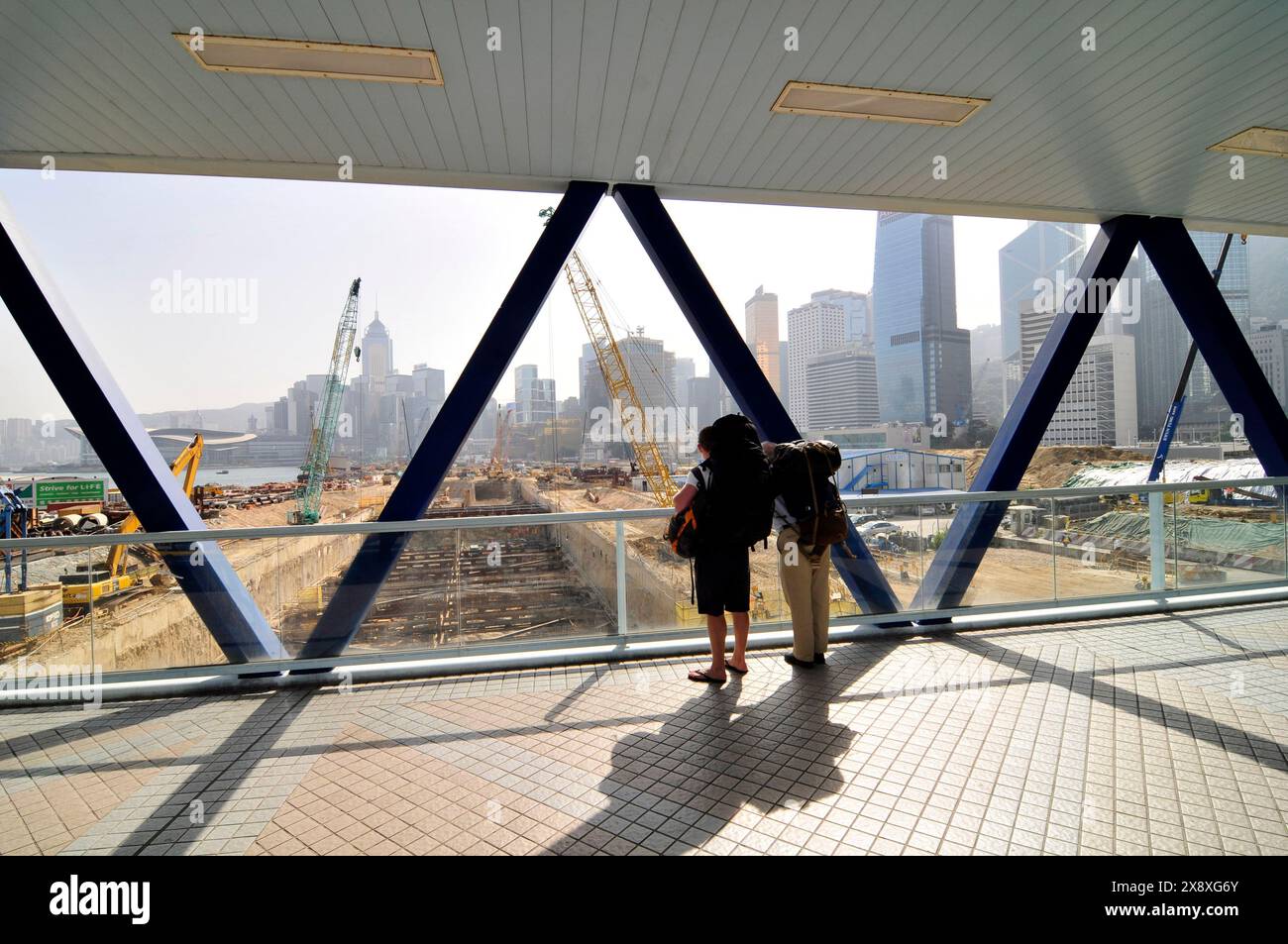 Turisti che guardano allo sviluppo del terreno bonificato vicino al centro commerciale IFC e al GPO di Hong Kong. Foto Stock