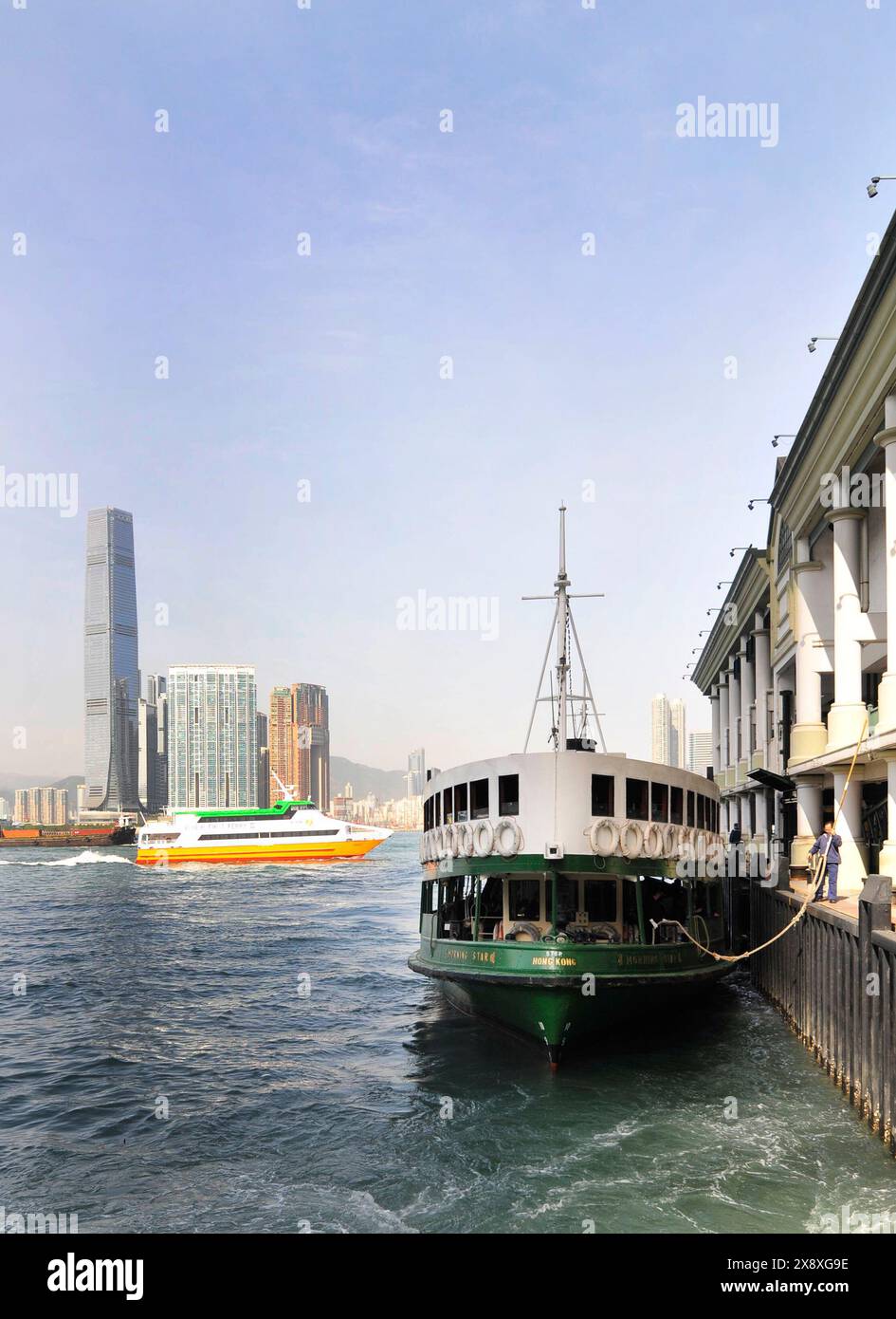 L'iconico attracco del traghetto Star al molo dei moli di Cental con vista del Porto Victoria e della torre ICC a Kowloon, Hong Kong. Foto Stock