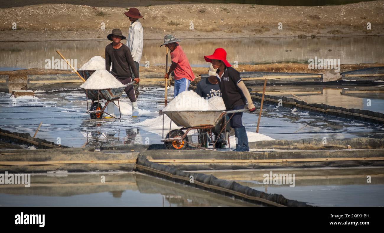 Un produttore di sale sta raccogliendo sale sotto il caldo sole estivo. Abitanti del villaggio che lavorano nelle fattorie di sale in Vietnam. Uomini che lavorano sodo. Maggio 8,2024 Foto Stock