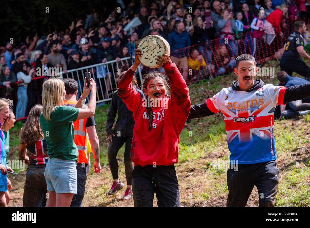 Gloucester, Regno Unito. 27 maggio 2024. Abby Lampe (23) dalla Carolina del Nord, USA celebra la sua vittoria nella gara femminile a Gloucester. La Gloucester Cheese Rolling Race è una competizione tradizionale sulla Copper's Hill a Brockworth, vicino a Gloucester, nel Regno Unito. Sta attirando persone a partecipare alla gara da tutto il mondo. I partecipanti inseguono un formaggio doppio Gloucester pesante da 3 chilogrammi su una collina lunga 200 metri e ripida di oltre 45 gradi. Credito: SOPA Images Limited/Alamy Live News Foto Stock