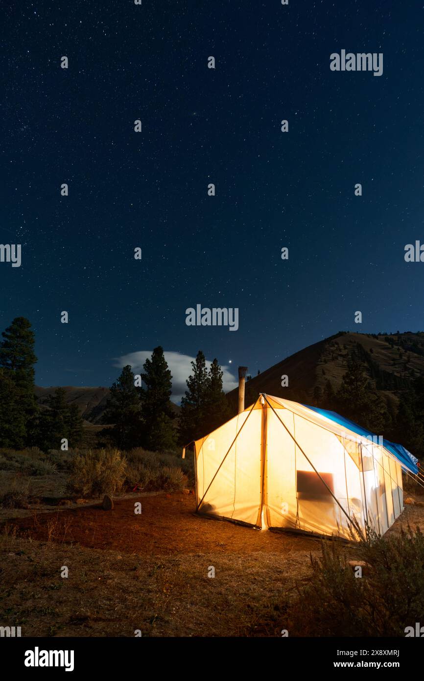 Tenda calda nel campo di caccia illuminata sotto il cielo stellato della notte, Thomas Creek, Frank Church River of No Return Wilderness, Idaho, Stati Uniti Foto Stock