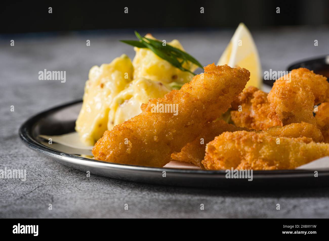 Tempura di gamberi fritti con insalata di patate su un piatto di metallo Foto Stock