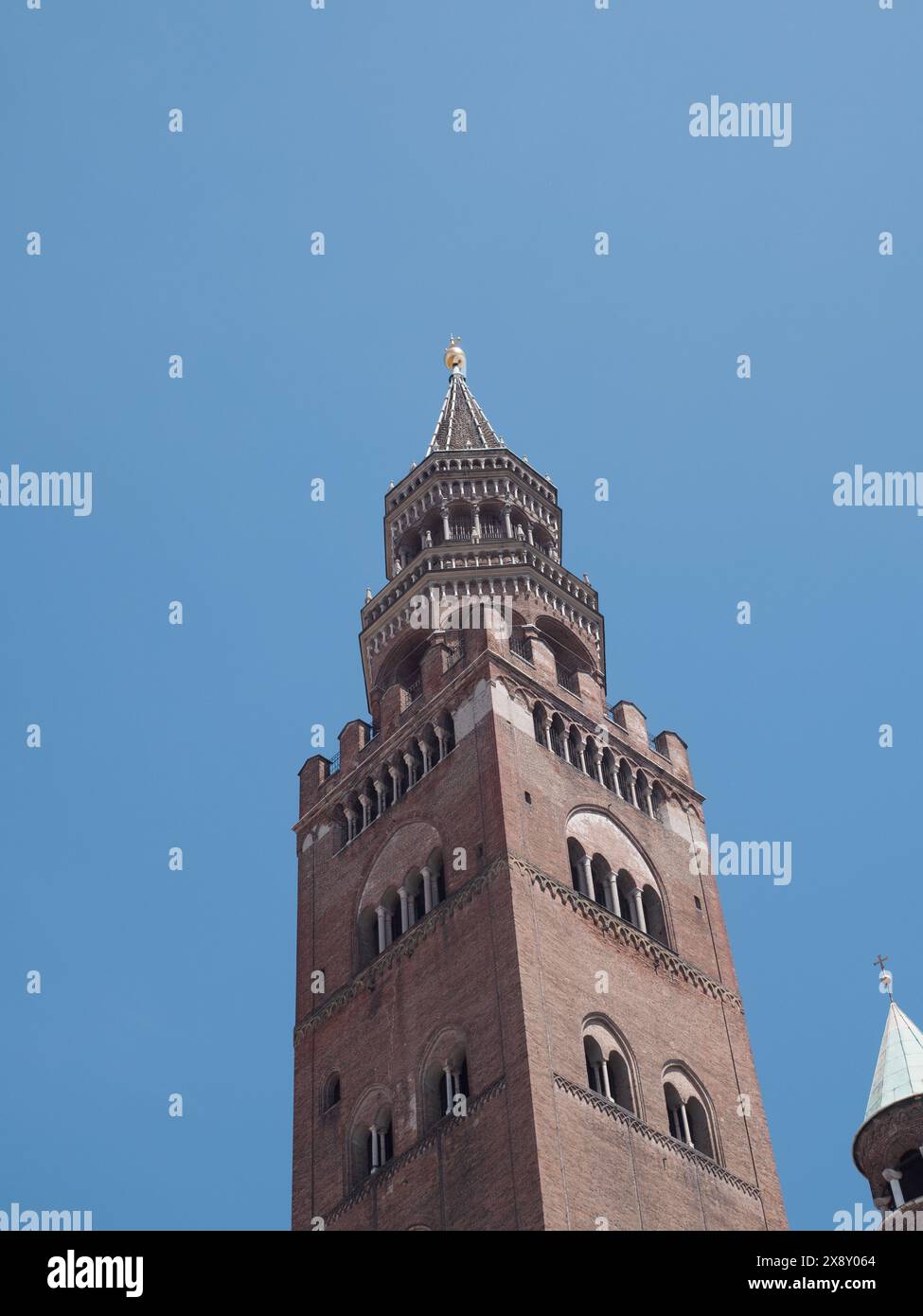 Cremona, Italia - 15 maggio 2024 si erge una splendida torre medievale in mattoni, che mostra intricati dettagli architettonici su un cielo blu vivace, che trasuda Foto Stock