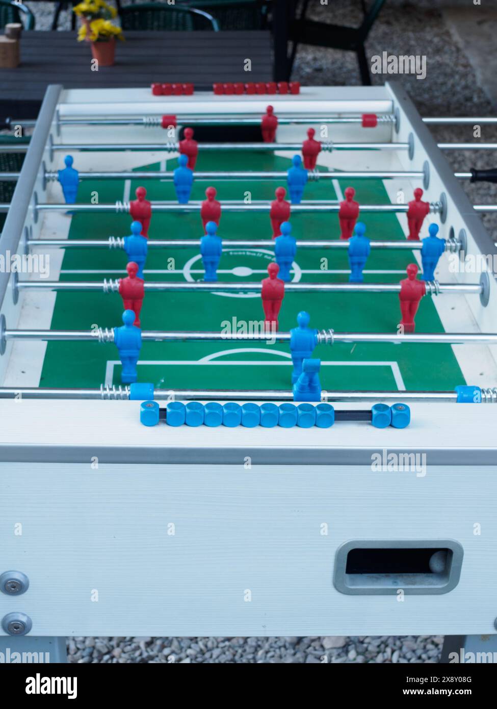 Vivace partita di calcio balilla pronta per il gioco, con figure rosse e blu allineate su un campo verde, all'aperto Foto Stock