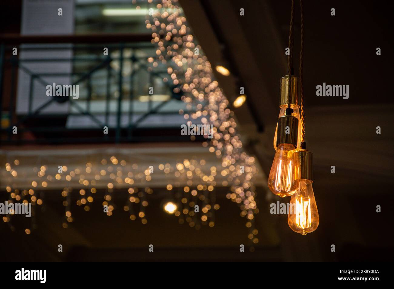 Ambiente interno caldo e accogliente con lampadine Edison vintage e luci bokeh festose. Perfetto per gli amanti degli ambienti intimi e dell'atmosfera di vacanza. Foto Stock