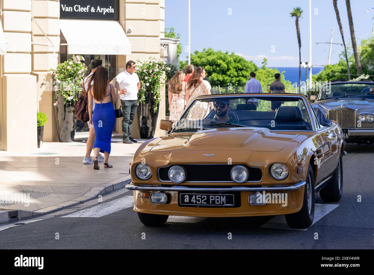 Monte Carlo, Monaco - Vista su una Aston Martin V8 volante Series 1 gialla in auto sulla Piazza del Casinò. Foto Stock