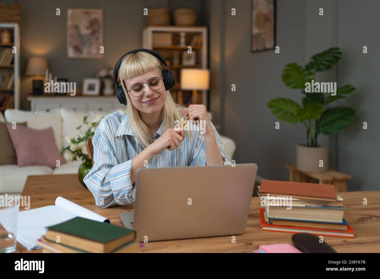 Auto miglioramento. Giovane studentessa soddisfatta o donna d'affari, che lavora al computer portatile da casa, impara dai libri, per implementare innovazioni in bu Foto Stock