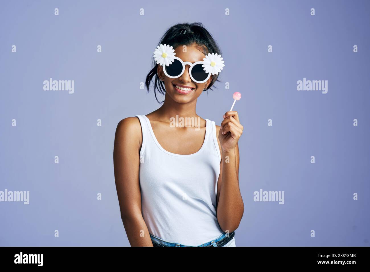 Occhiali da sole da ragazza ritratti e divertenti come gen z su sfondo blu per moda stile ed energia. Persona femminile felicita e lecca lecca in giocosa Foto stock Alamy