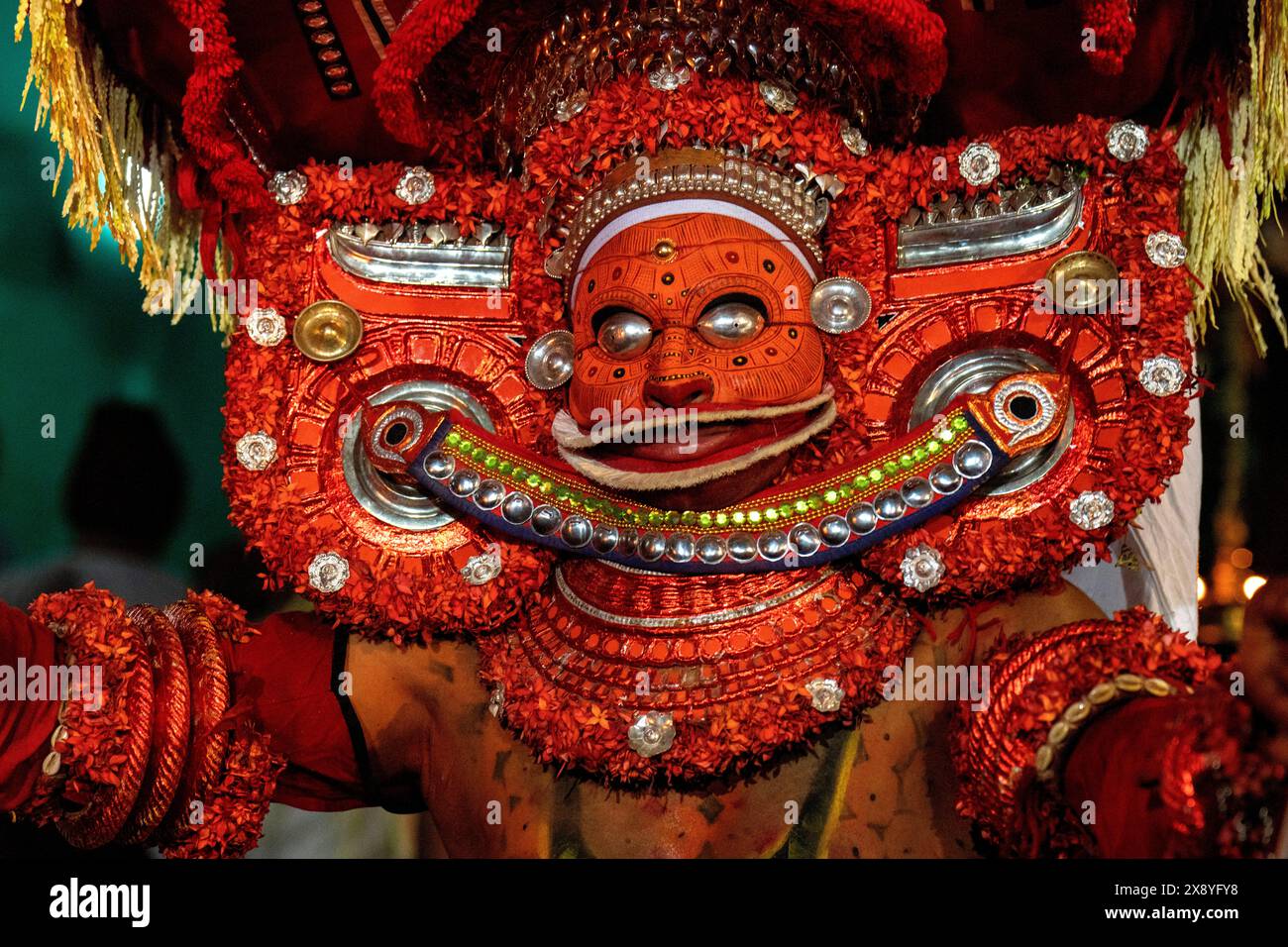 India, Kerala, Kannur, cerimonia Theyyam. Splendidamente vestiti e con i loro volti dipinti interamente di rosso, gli artisti possono assumere la forma di più de locali Foto Stock