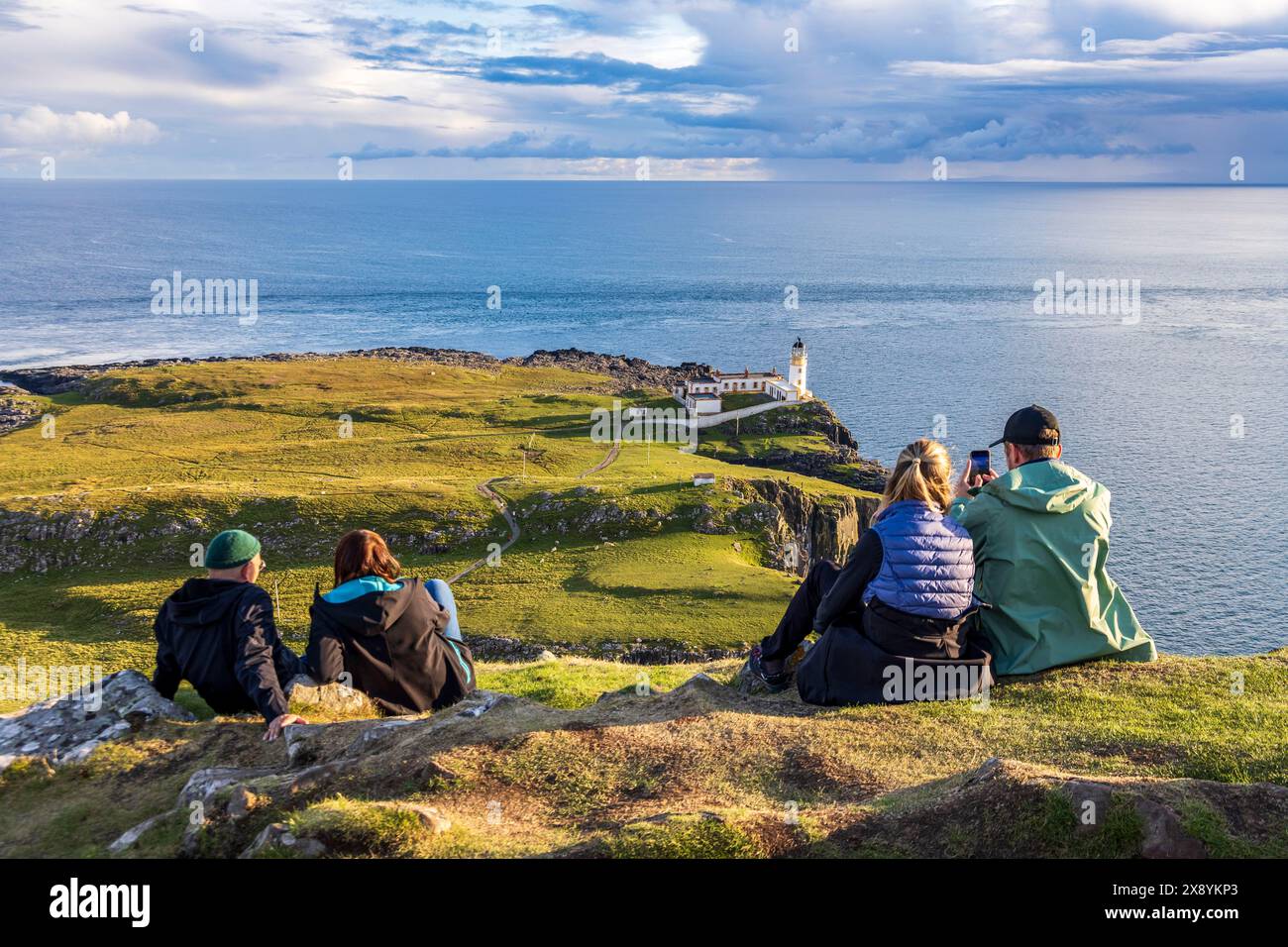 Regno Unito, Scozia, Highlands, Isola di Skye, due coppie che viaggiano ammirano lo splendido paesaggio e il faro di Neist Point Foto Stock
