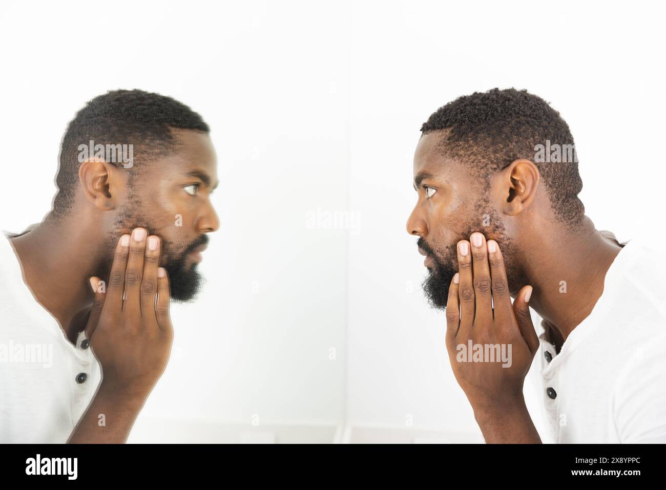 A casa in bagno, uomo afroamericano che tocca il mento, esamina il viso Foto Stock