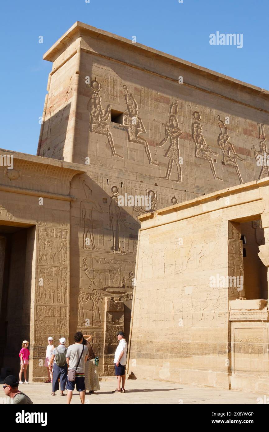 Turisti al Pylon, al complesso del Tempio di Philae, all'isola di Agilkia, al bacino idrico della diga di Assuan. Luogo di sepoltura di Osiride. Egitto Foto Stock