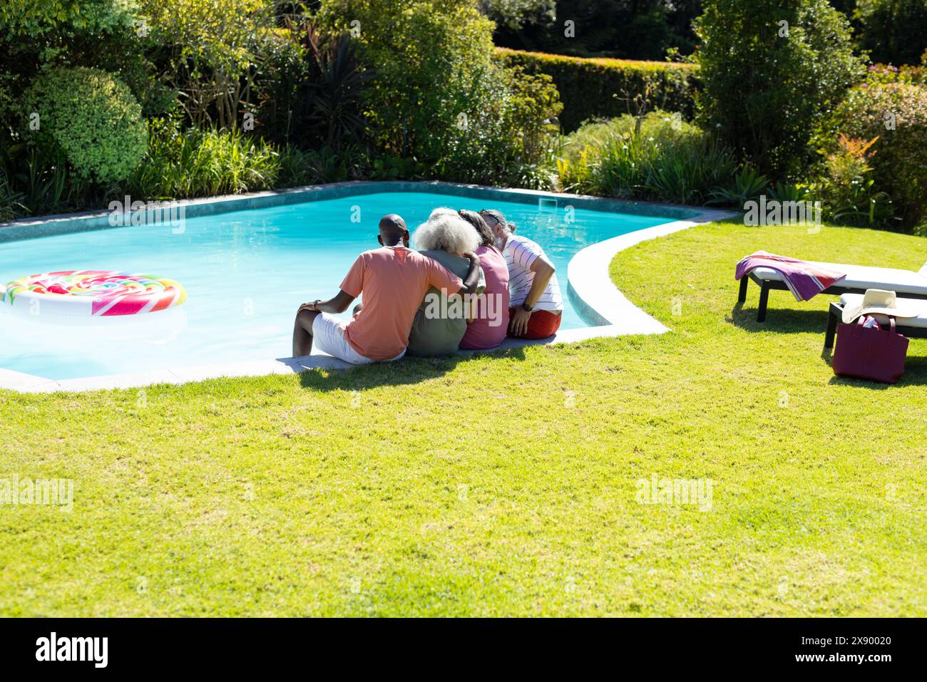 All'aperto, diversi amici anziani si rilassano a bordo piscina e si godono il sole Foto Stock